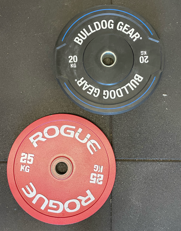 A calibrated Rogue 25kg plate beside a Bulldog Gear Hybrid 2.0 rubber bumper plate